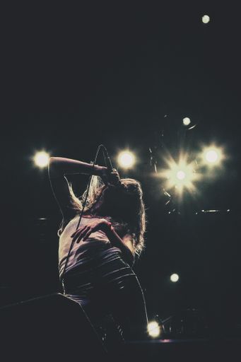 A vertical shot of a female singer holding a microphone on stage with a blurred background
