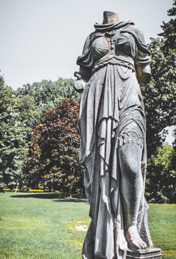 A vertical shot of an ancient broken statue in the park.