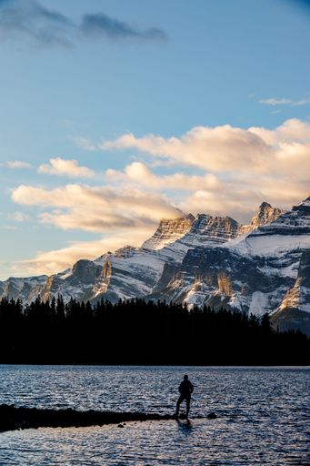 A silhouette of a man at the Lake Loraine in Canada admiring the view of the mountains