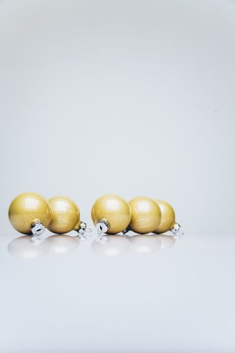 A vertical shot of gold colored Christmas ornaments on a white surface