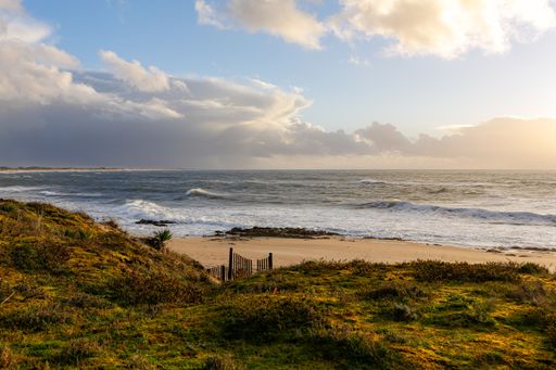 A mesmerizing view of the beach and waves in the sea under a cloudy sky