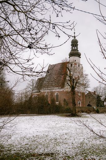 A beautiful shot of the Church of the Holy Trinity Malkowice on snow winter ground with a light sky, Poland