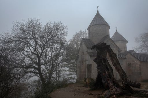 A beautiful view of Haghartsin Monastery Complex with trees against a hazy gray sky, Dilijan, Armenia