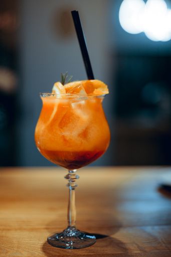 A shallow focus shot of a Spritz Veneziano cocktail on a wooden table