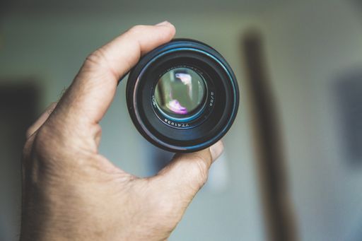 A closeup shot of a person holding a camera lens with a blurred background