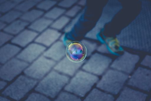 A selective closeup focus shot of a floating bubble with a running person in the background in the evening
