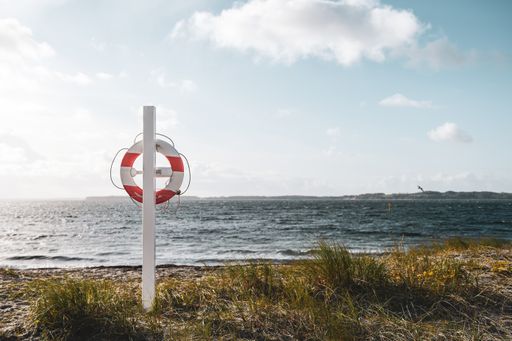 A lifebuoy ring on a white wooden post by the seashore