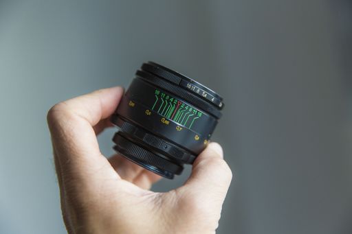 A selective closeup focus shot of a person holding a black camera lens with a blurred background