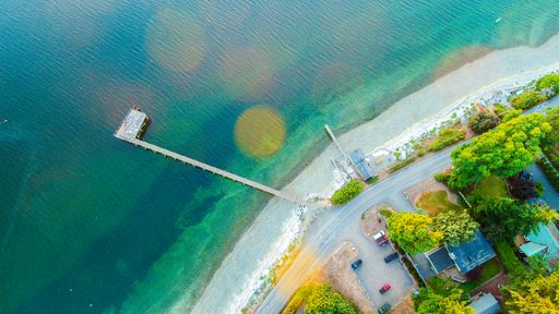 A drone shot of the seacoast with an empty dock during daytime