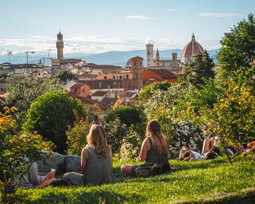 Group of friends sitting on the grass with a beautiful view of Florence at the background on a clear blue pring day