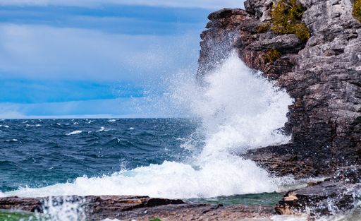 A beautiful view of splashing sea waves with rocky cliffs in Tobermory, Canada