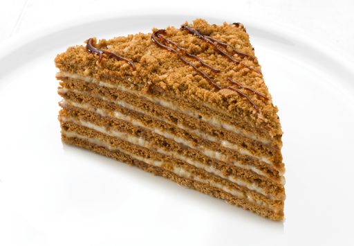 A closeup of a slice of delicious honey cake on a plate isolated on a white background