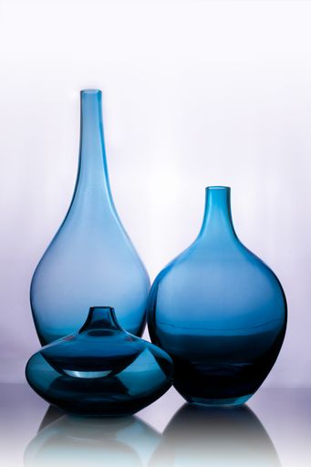 A vertical closeup shot of blue glass vases isolated on a white background