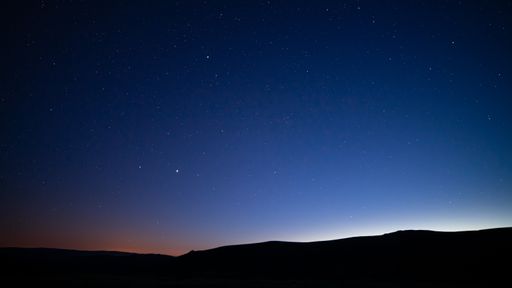 The silhouettes of hills under a starry sky at night - perfect for wallpapers and backgrounds