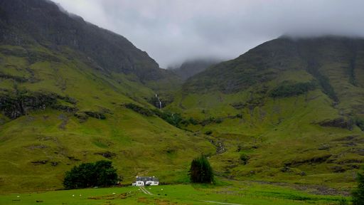 A landscape of hills covered in the fog and greenery under a cloudy sky at daytime