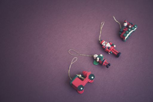 A high angle shot of Christmas tree hanging ornaments with a purple background