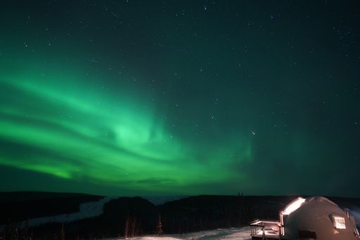 A horizontal shot of the Northern lights (aurora borealis) in a green and blue hue