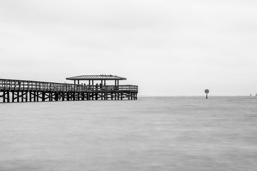A greyscale shot of a fishing pier at the Safety Harbor in Florida