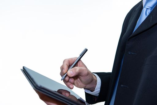 Unrecognizable businessman with a tablet using a digital pen, white background, copy space