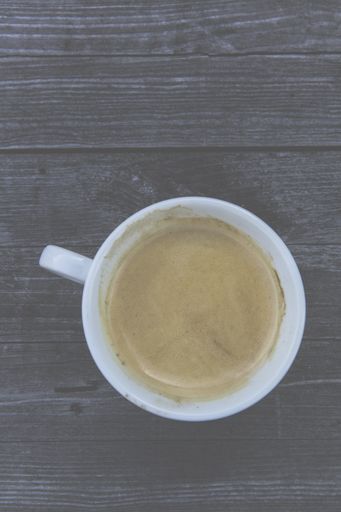 A high angle shot of a cup of coffee on a wooden surface