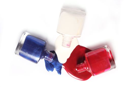 A top view of colorful spilled nail polish on white surface