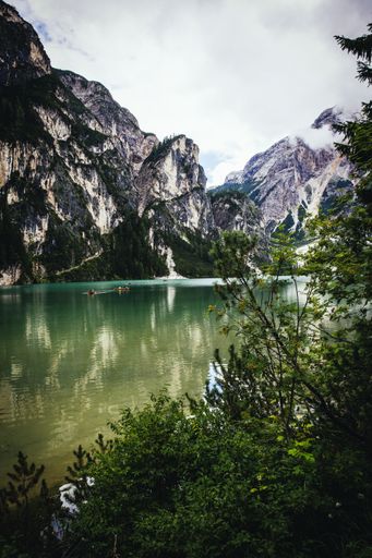 A beautiful vertical shot of a lake surrounded by rocky mountains and trees