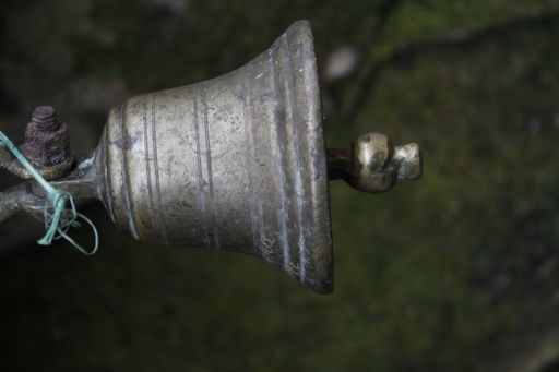 An old rusted metalic hanged bell on a blurry green background