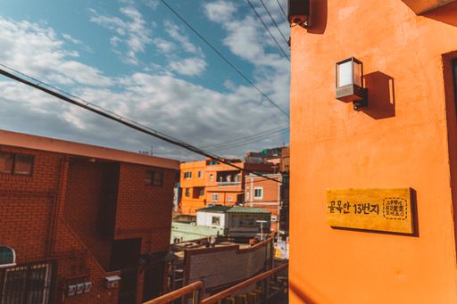 A low angle shot of an orange building facade with a wooden sign with Chinese writings on a cloudy sky background