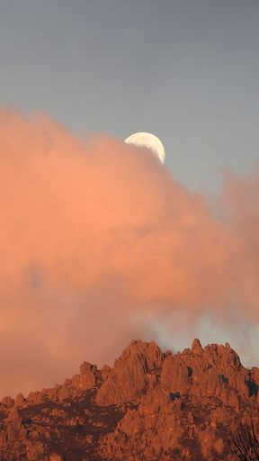 A vertical shot of the orange clouds covering moon and rocks