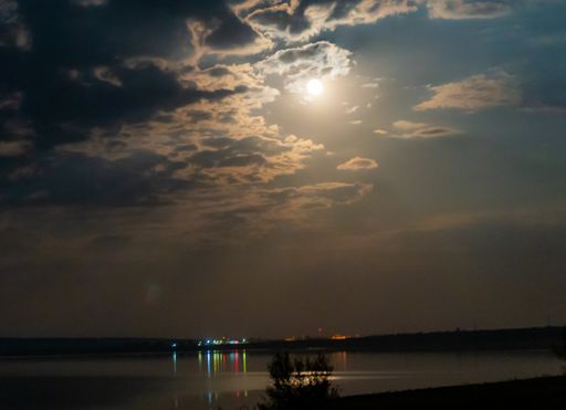 A low angle shot of a reflective lake under a bright moonlight
