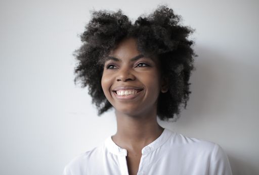 An attractive African-American female with a wide smile standing against a white wall