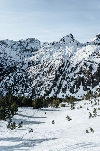 A Vertical shot of a snowed mountain with forest at the valley on a high clouds day on Tavascan Area