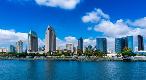 A beautiful view of a city with tall buildings from a sea under the blue sky