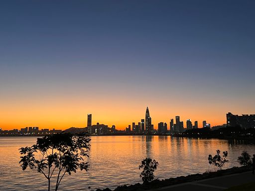 A mesmerizing shot of a sunset opening from the sea with a pretty view of the city
