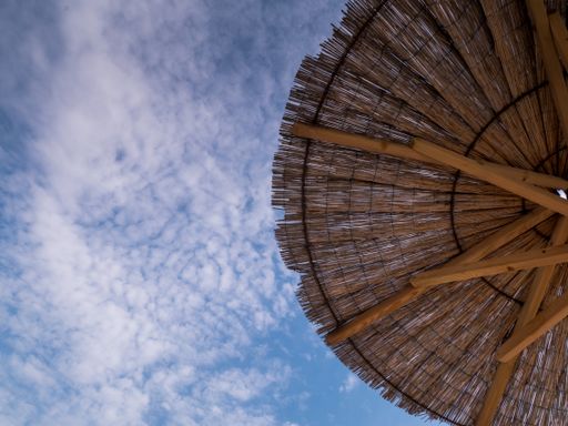 A low angle shot of a straw beach umbrella under the sunlight and a blue cloudy sky in Croatia