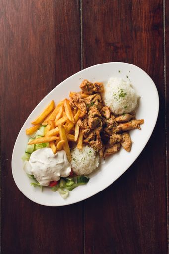 A vertical shot of chicken pieces with fries, rice and vegetables
