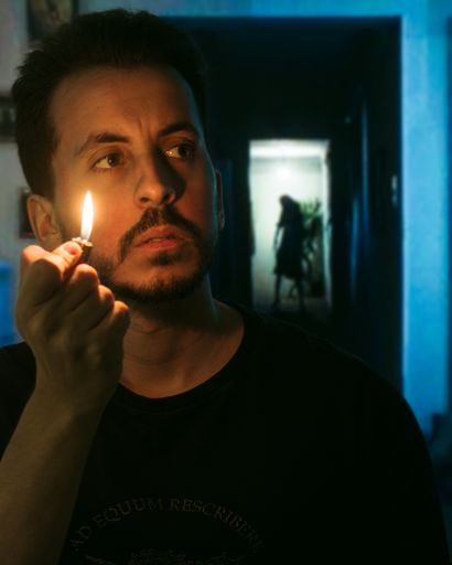 A person in the foreground holding a lighter with a terrifying silhouette behind. horror scene