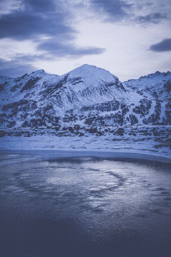 A scenic shot of mountains covered in snow under the beautiful cloudy sky in winter