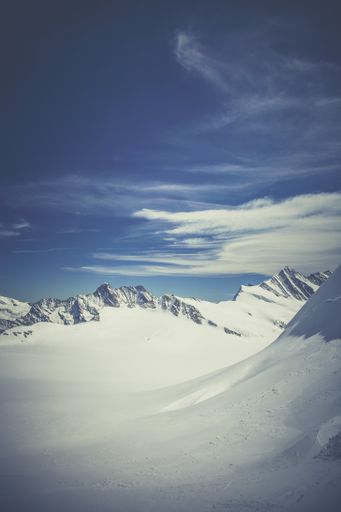 A beautiful scenery of Snowy Swiss mountainscape covered in snow under the cloudy sky in winter