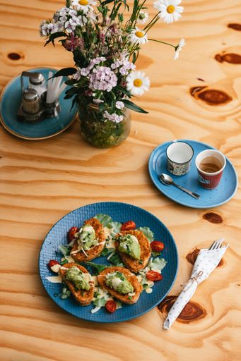A vertical shot of a french toast with avocado spread, vegetables and espresso