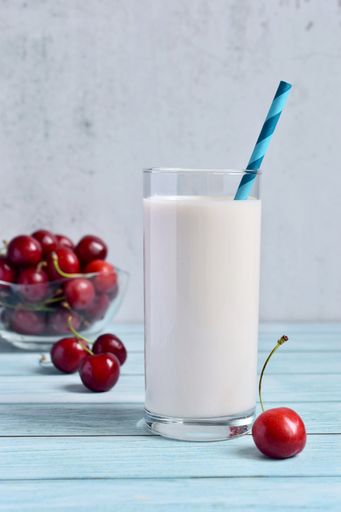 A vertical shot of a glass of milkshake with cherries
