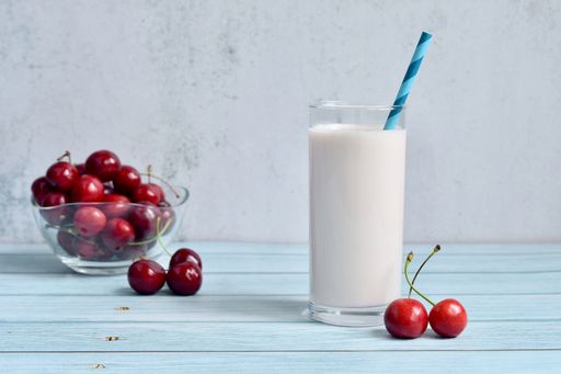 A closeup of a milkshake and cherries in a bowl