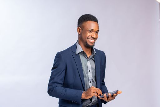 A happy African businessman calculating his costs and profit using a calculator