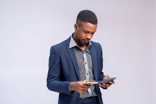 A young African businessman calculating his costs and profit using a calculator