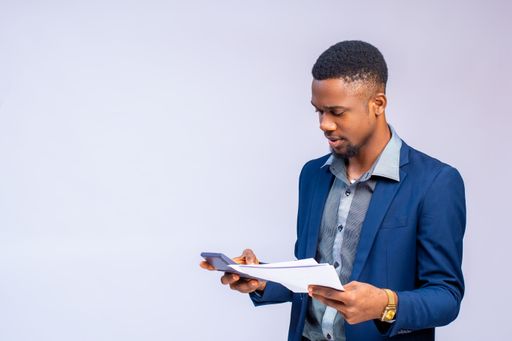 An African business man holding papers isolated on white background