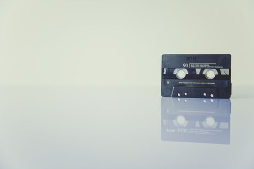 A black cassette tape with the reflection on white surface