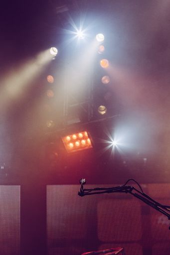 A vertical shot of a microphone with spotlights in the background during a concert