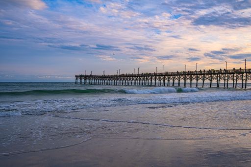 A beautiful view under a wooden pier on a water beach on the coast of North Carolina.