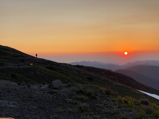 A silhouette of a person standing on a mountain during a beautiful sunset in the evening