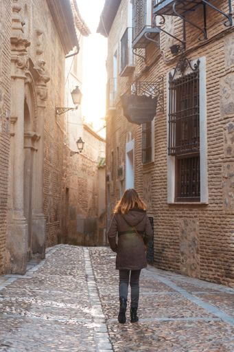 A vertical shot of the woman walking down the street in Toledo, the medieval city of Castilla La Mancha. Spain.